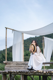 身穿白色长裙的少女坐在户外的木栈道上