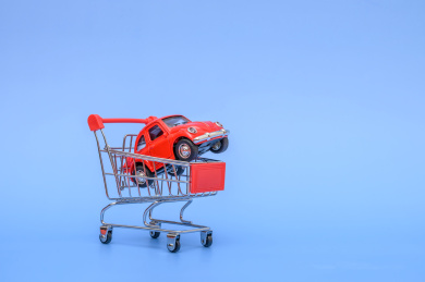 蓝色背景前的购物车和小汽车概念