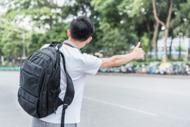 在马路边招手打车的男青年背面