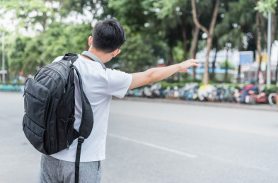 在马路边招手打车的男青年背面
