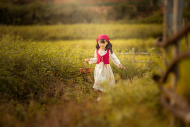 夕阳下一个身着裙子的小姑娘走在稻田间游玩