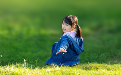 坐在草坡上扭头看的小女孩