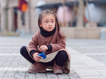 蹲在地上手拿饼干包装纸的中国小女孩