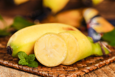 藤垫上放着一根小香蕉和一根切块的小香蕉