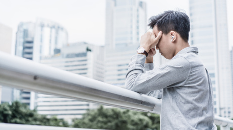 沮丧的商务人士靠着栏杆双手捂脸