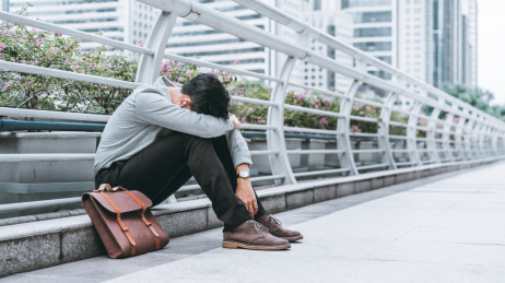 失败的商务人士沮丧地坐在天桥边