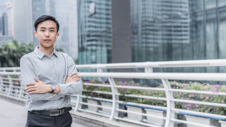 自信的商务人士双手环抱站在天桥上