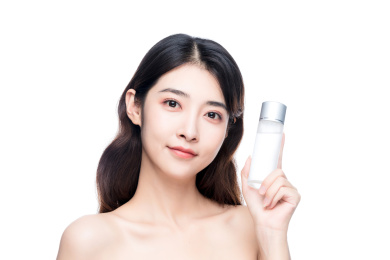 年轻亚洲美女手拿护肤品白色背景半身肖像