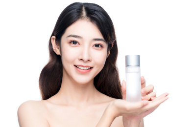 年轻亚洲美女手拿护肤品白色背景半身肖像