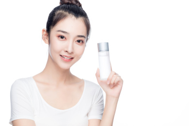 年轻亚洲美女手拿护肤品白色背景半身肖像
