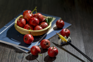 山楂红果摆放在放有线装书的木桌面上