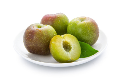 云南半边红脆李和切开果肉带绿叶装白盘白底