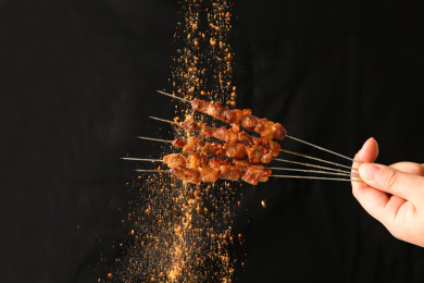 黑色背景下烧烤的撒调料瞬间