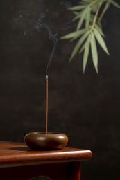点燃的线香摆放在红木茶几上黑色背景