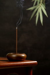 点燃的线香摆放在红木茶几上黑色背景