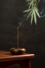 点燃的线香摆放在红木茶几上黑色背景
