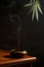 点燃的线香摆放在红木茶几上黑色背景