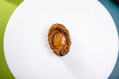 蓝绿色卡纸上放着一份鲍汁海参