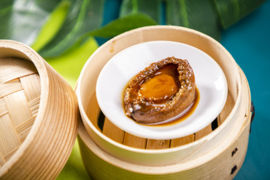 蓝绿色卡纸上放着一份鲍汁海参