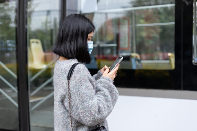女孩戴着口罩在公交站等车