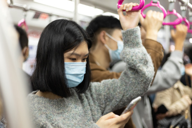 女孩戴着口罩乘地铁 低头看手机