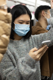 女孩戴着口罩乘地铁 低头看手机