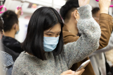 女孩戴着口罩乘地铁 低头看手机
