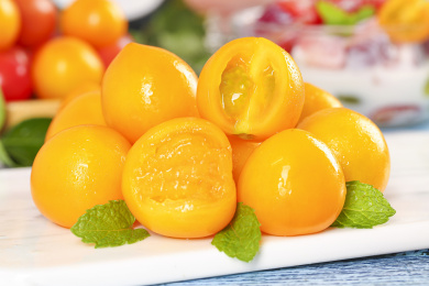 白石板上放着一堆黄色小番茄和切开的圣女果