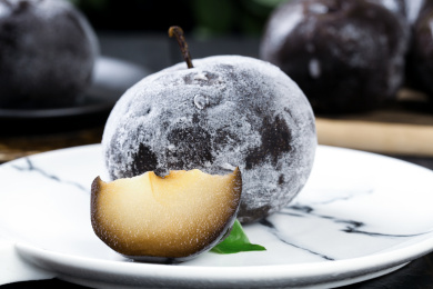 白石盘上放着一个完整的冻梨和切块的冻梨