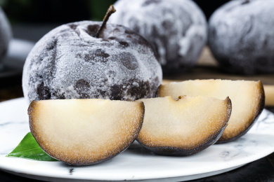 白石盘上放着一个完整的冻梨和切块的冻梨