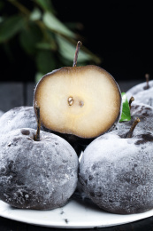 黑底上放着一盘东北冻梨和一个切面的冻梨