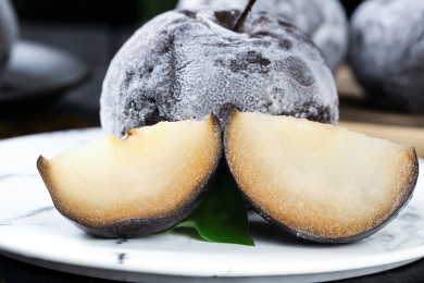 白石盘上放着一个完整的冻梨和切块的冻梨