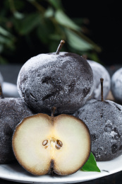 黑底上放着一盘东北秋冻梨和一个切面的冻梨