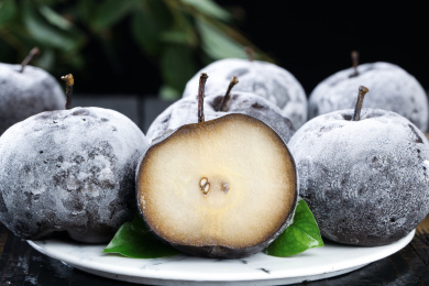 黑底上放着一盘东北秋冻梨和一个切面的冻梨