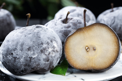 盘子上放着两个完整的冻梨和一个切面冻梨