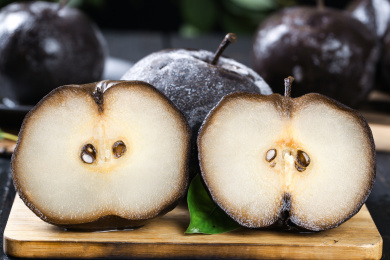 木垫上放着一个完整的秋冻梨和两个切面冻梨