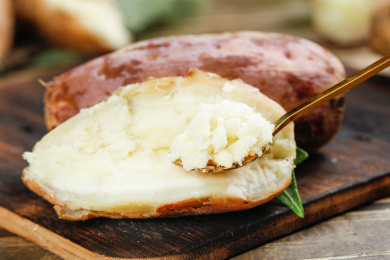 黑底上半边白心蜜薯和勺子上挖着蜜薯