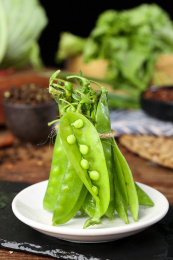 黑底盘子里放着青豆荚