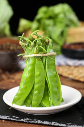 黑底盘子里放着青豆荚