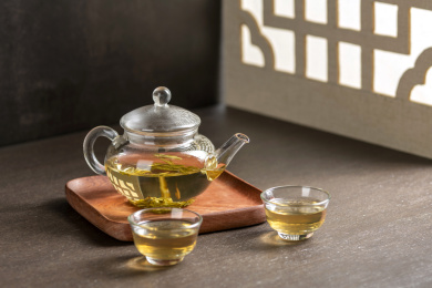 仿古玻璃茶壶冲泡的茶水摆放在窗棂影木桌面