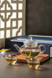 仿古玻璃茶壶冲泡的茶水摆放在窗棂影木桌面