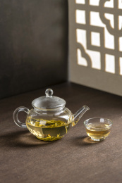 仿古玻璃茶壶冲泡的茶水摆放在窗棂影木桌面