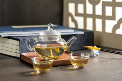 仿古玻璃茶壶冲泡的茶水摆放在窗棂影木桌面