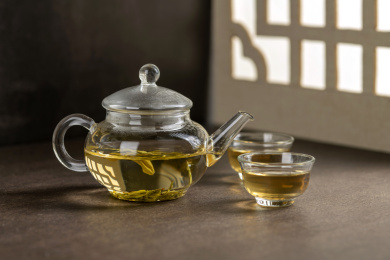 仿古玻璃茶壶冲泡的茶水摆放在窗棂影木桌面