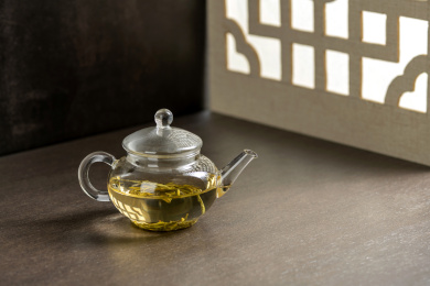 仿古玻璃茶壶冲泡的茶水摆放在窗棂影木桌面