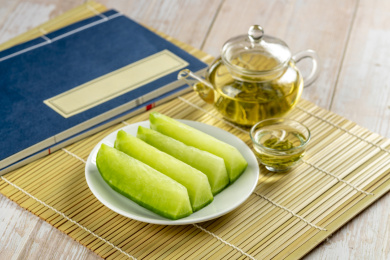 青萝卜茶水线装书摆放在铺着竹帘的木桌面上
