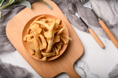 桌面上的木粘板上的木盘子里的萝卜条干