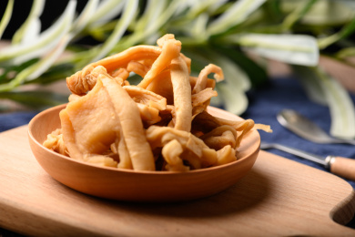 桌面上的木粘板上的木盘子里的萝卜条干