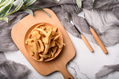 桌面上的木粘板上的木盘子里的萝卜条干