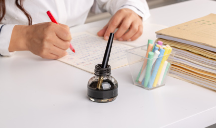 老师手拿红笔为学生批改作业特写